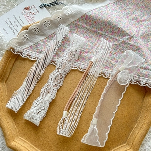 Set of four white lace baby headbands with delicate floral embroidery on wooden tray