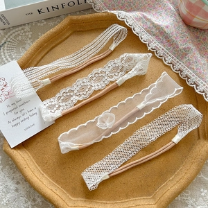 Detail view of four assorted white lace and embroidery baby headbands on a tray