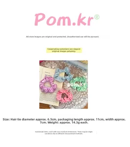 Detail view of colorful satin scrunchies featuring white pearl embellishments and lace edges
