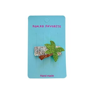 Sparkly coconut tree hair clip with green sequins for girls on light blue display card