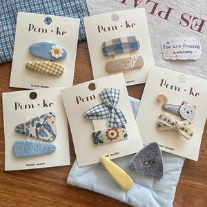 Detail of handmade fabric hair clips with floral patterns and cute cat designs for girls