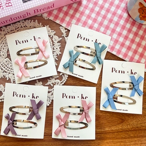 Detailed set of colorful fabric bow hair clips on display card with soft aesthetic