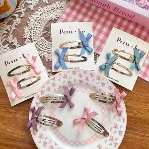 Pastel bow hair clip set with pink, blue, and purple ribbons on a floral ceramic display