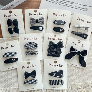 Set of 10 pairs black and white checkered bow hair clips with pearls on a wooden desk