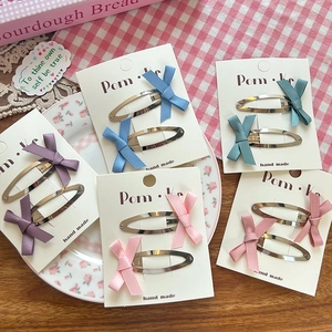 Close-up of five colorful ribbon bow hair clips in purple, blue, green, and pink colors