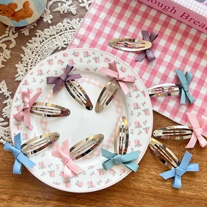 Set of colorful ballet-style ribbon bow hair clips on a decorative floral ceramic plate