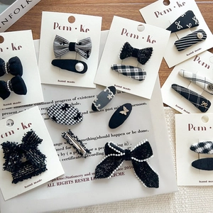 Set of black and white bow hair clips with houndstooth and pearl details on white background