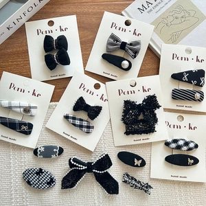 Detailed flat lay of black and white plaid bow hair clips with pearls on a wooden desk