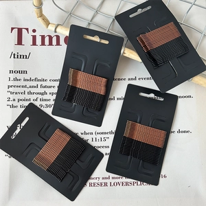Minimalist black and bronze wave snap hair clip set in organized cardboard packaging