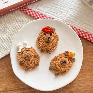 Three cute knitted capybara hair clips with crochet embroidery and little hats for kids