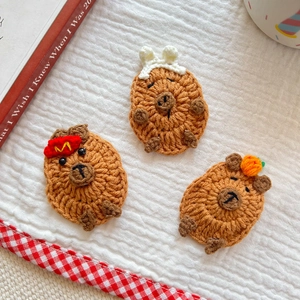 Close-up of handmade crochet capybara hair clips with mini pumpkin and bunny ear details