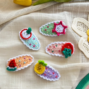 Detailed view of handmade crochet fruit hair clips set with strawberry and watermelon patterns