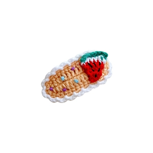 Handmade crochet strawberry hair clip with colorful dots and lace edges on white background
