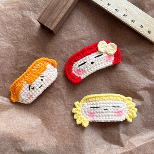Détail de trois barrettes à cheveux crochetées à la main avec visages de filles en dessin animé