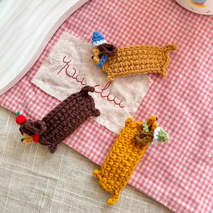 Handmade crochet dachshund hair clips for kids in three colors on a plaid background