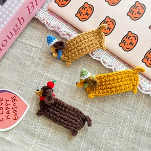 Detailed close-up of three handmade crochet dachshund hair clips with cute hats for girls