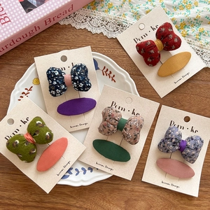 Gros plan de barrettes à fleurs en tissu et épingles ovales de style vintage champêtre