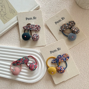 Vue détaillée des barrettes à fleurs et chouchous à pompons aux couleurs douces