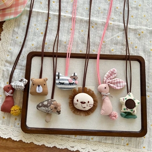 Detail of assorted handmade plush animal necklaces featuring bears and lions on lace