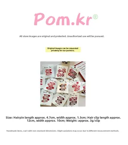 Detail view of red floral drop hair clips and wave-shaped hairpins on white display cards