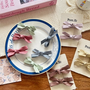 Sweet Korean pearlescent bow hair clips in multiple colors on a chic French ceramic plate