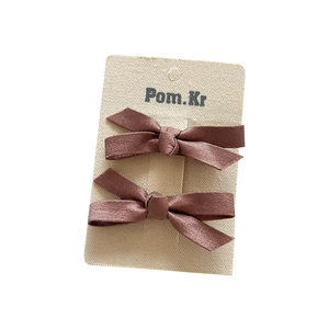 Set of two brown pearlescent bow hair clips for girls on a beige display card