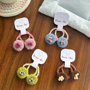 Détail de quatre paires d'élastiques à fleurs tricotés main sur des cartes de marque