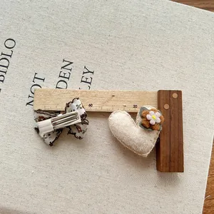 Detailweergave van handgemaakte vilten hart en bloemen haarclips met textuur en maat