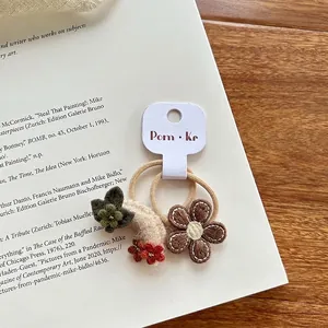 Detail van handgebreide haaraccessoires met bloemen en maan op een presentatiekaart