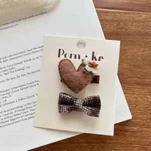 Detail van handgemaakte haarclips set met hart en strik op vintage boekachtergrond