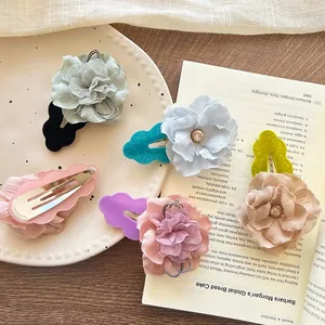 Detailed view of handmade fabric flower hair clips with rhinestones and pearl centers