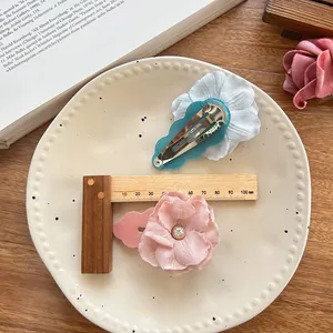 Close-up of floral fabric hair clips with rhinestones in a white ceramic dish
