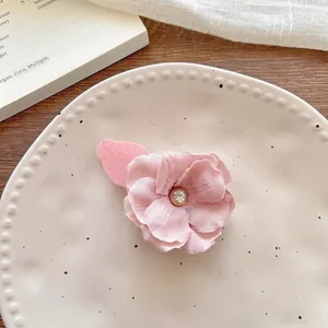 Macro detail of a pink fabric flower hair clip with a sparkling rhinestone center