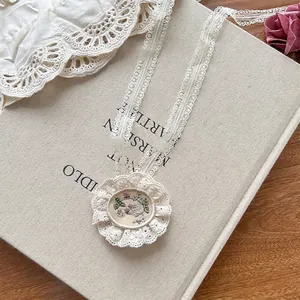 Detail shot of vintage lace choker with a delicate floral embroidery oval pendant