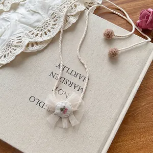 Detail showing beige handcrafted lace flower embroidery pendant and soft braided rope