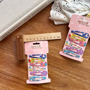 Detail of colorful cartoon unicorn and rainbow snap hair clips for girls on pink card