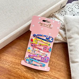 Close-up of 6 colorful kids metal hair clips with unicorn and fruit prints on wood background