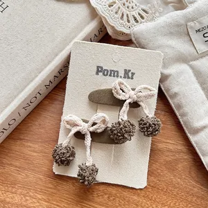 Détail de pinces à cheveux vert foncé avec nœuds tissés main et pompons en peluche