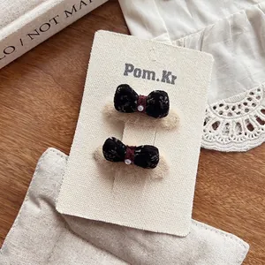 Vue détaillée de pinces à cheveux à nœud en tissu floral avec perle sur carte