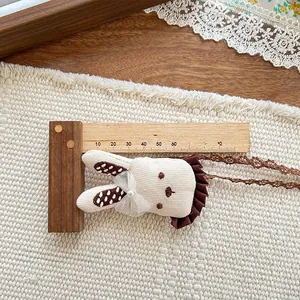 Detail view of a 70mm cream knitted bunny pendant with lace bow and pearl accent