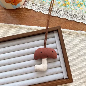 Detailed close-up of a handmade mushroom fabric pendant with brown polka dot pattern