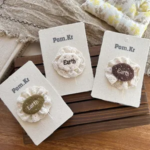 Dettaglio di tre fermagli per capelli vintage in pizzo con ricamo Earth in colori naturali