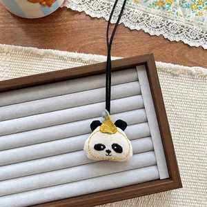 Close-up of cute panda fabric pendant with embroidery and yellow hat on a jewelry tray