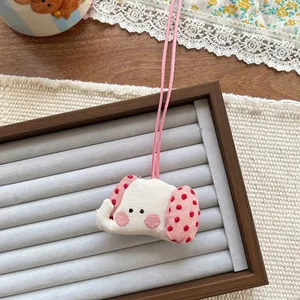 Detailed view of elephant plush charm with red polka dot ears on a display tray