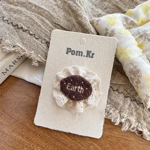 Dettaglio del fermaglio per capelli orsetto in pizzo caffè latte con ricamo Earth e bordi