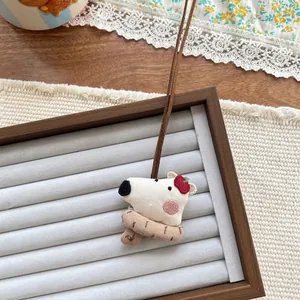 Detailed close-up of a white polar bear fabric pendant with a brown knitted scarf
