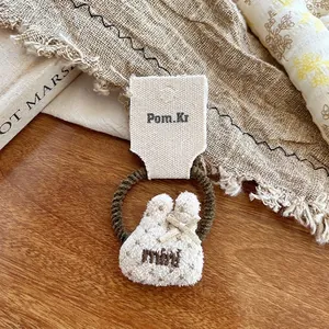 Dettaglio dell'elastico per capelli con coniglio in peluche crema e piccolo fiocco