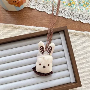 Close-up of rabbit plush pendant with knit texture, brown polka dots and lace strap