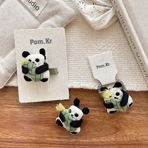 Cute plush panda hair clip and scrunchie set with bamboo accent on a natural desk