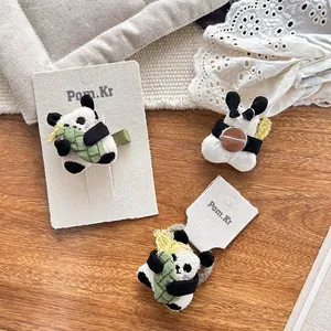 Detail of plush panda hair clip and brooch with bamboo accent on wood background